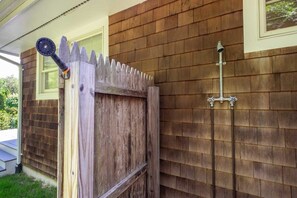 A wooden gate with a picket design, a metal gate latch, and a metal pipe attached to the wall.