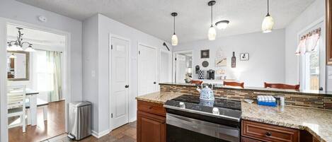 A modern kitchen with a central island, stainless steel appliances, and pendant lighting.