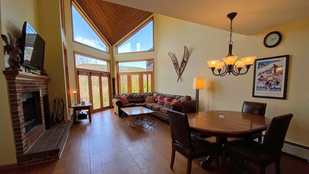 A spacious living room with a fireplace, large windows, a dining area, and a chandelier. - C3 Crawford Ridge Townhome With Views Walk to ski Lodge (Bretton Woods)