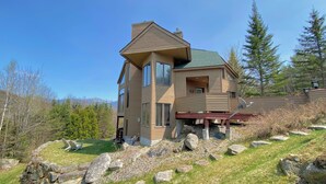A multi-story house with a sloped roof, large windows, and a deck. - C3 Crawford Ridge Townhome With Views Walk to ski Lodge (Bretton Woods)