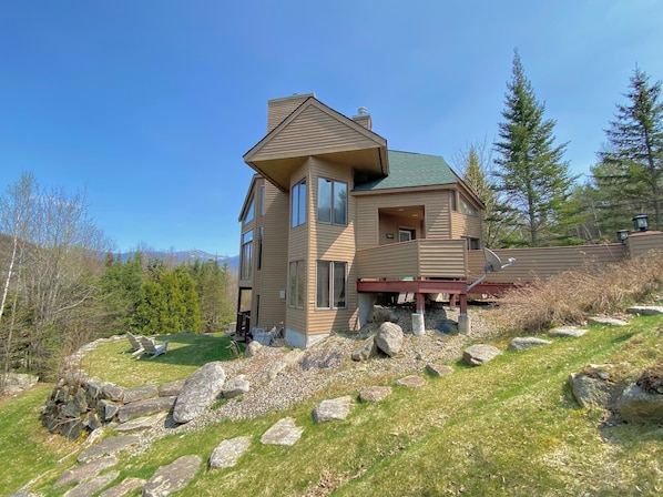 A multi-story house with a sloped roof, large windows, and a deck.