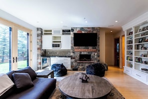 Una sala de estar moderna con una chimenea de piedra, un televisor de pantalla plana, un sofá, una mesa de centro y una estantería.