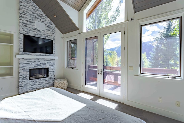 Un dormitorio con chimenea de piedra, ventanas amplias y vistas al exterior.