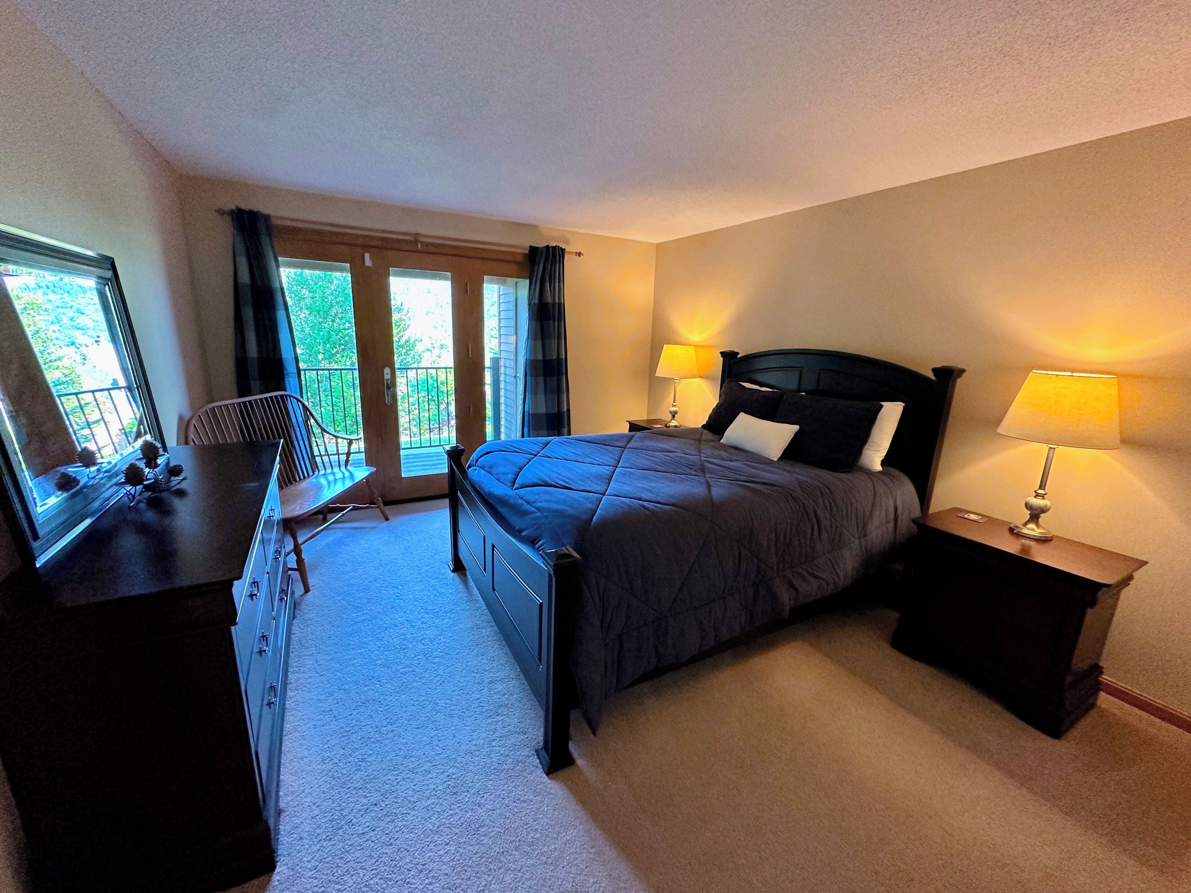A bedroom with a bed, two bedside lamps, a desk, and a chair.