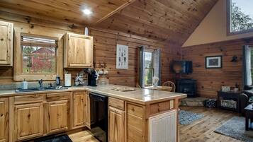 L’intérieur d’un chalet en bois comprend une cuisine, un coin repas et une cheminée.