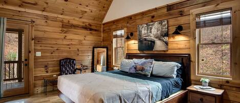 Une chambre dans une cabane en bois, avec un lit, une table de chevet, une chaise et une fenêtre.