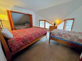 A bedroom with two beds, a dresser, a lamp, and a window.