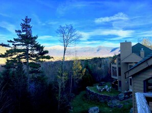 A house with a stone patio and outdoor seating, surrounded by trees and mountains in the background. - CR6 C6 Renovated Townhome a Short Walk From the Slopes Pool gym Passes (Bretton Woods)