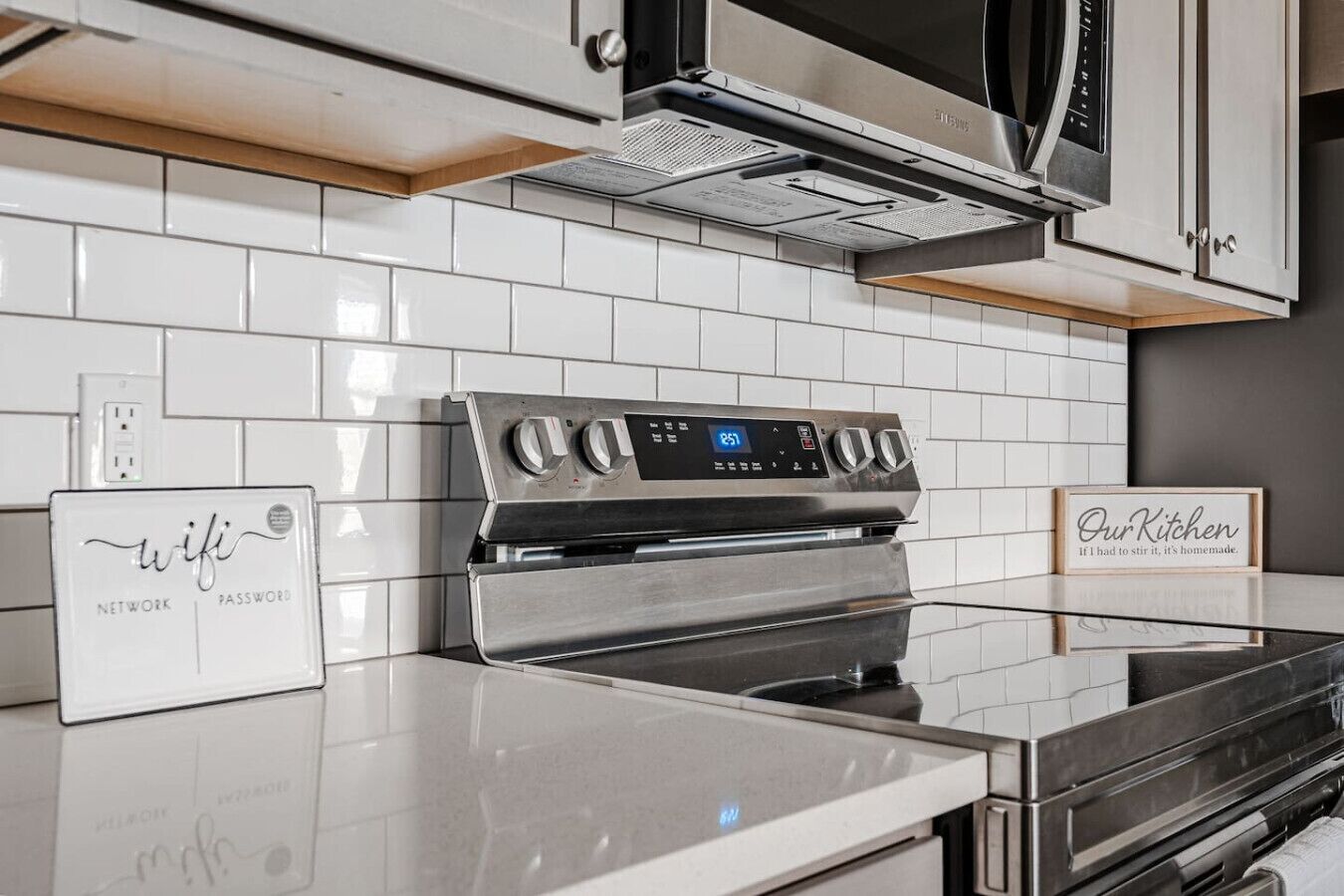 Eine moderne Küche mit Edelstahlgeräten, einer weißen Fliesenküchenwand und einem digitalen Display am Backofen.
