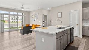 A modern kitchen with a central island, grey cabinets, and a large window overlooking a parking area. - Spacious Whitestown Getaway (Whitestown)