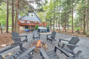 A deck with Adirondack chairs, a fire pit, and a house in the background. - Lakefront Hot Tub Kayaks High End Peaceful (Tobyhanna)