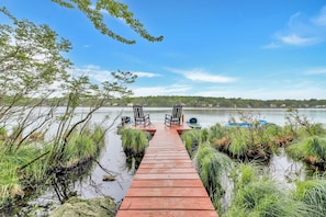 A wooden dock leading to a calm lake with two chairs facing the water, surrounded by greenery. - Lakefront Hot Tub Kayaks High End Peaceful (Tobyhanna)