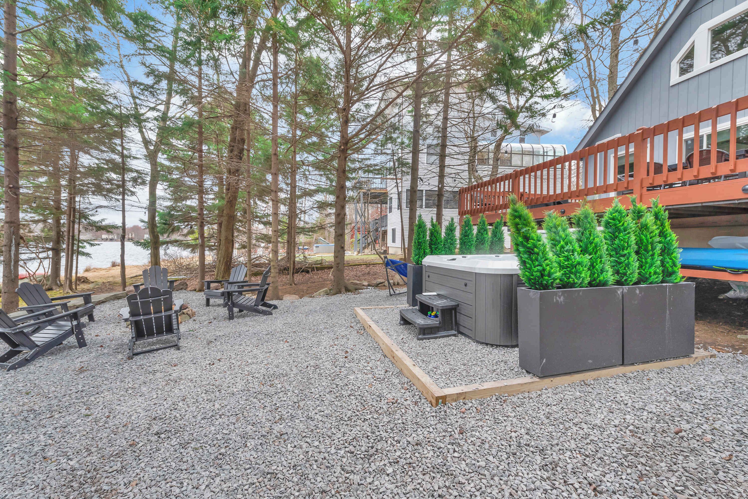 A patio with Adirondack chairs, a hot tub, and a wooden deck.
