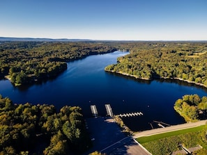 An aerial view of a lake surrounded by dense forest, with a dock and a road leading to it. - Authentic Log Cabin Short Walk to Lake & Hideout (Lake Ariel)
