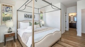 Una cama con dosel, una mesita de noche con lámpara, y un cuadro enmarcado en la pared.