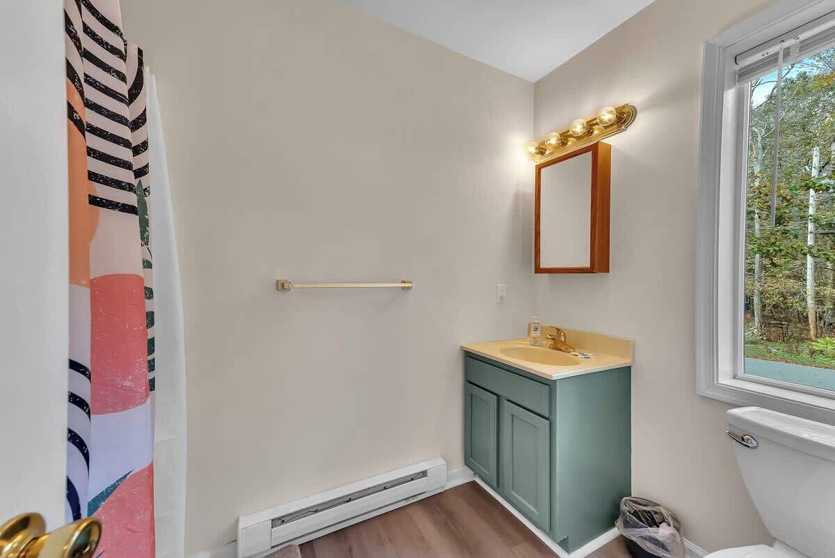 Une salle de bain équipée de toilettes, d’un lavabo, d’un meuble-lavabo et d’une fenêtre donnant sur un paysage agréable.