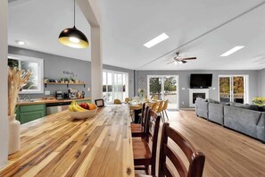 A spacious living area with a wooden dining table, chairs, a sofa, a TV, and a fireplace. - Lakefront, Hot Tub, Kayaks, Firepit, Pool Table (Tobyhanna)