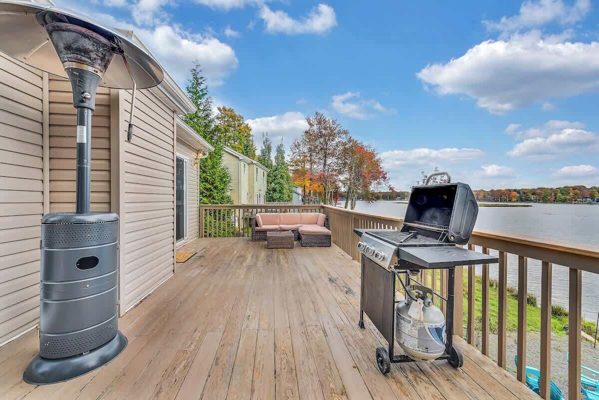 A deck with a grill, a trash can, and a patio area with a sofa.