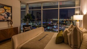 Quarto de hotel com uma janela grande que oferece vista da cidade à noite.