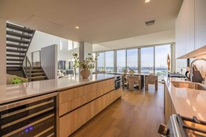 Une cuisine moderne dotée d’un îlot central, d’un escalier et de grandes fenêtres offrant une vue sur la ville.