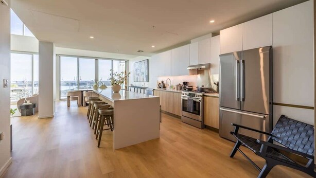 Uma cozinha moderna com ilha central, eletrodomésticos de aço inoxidável e vista para a cidade.