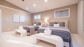 A bedroom with two beds, a bench, and a ceiling fan.
