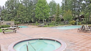A pool area with a hot tub, picnic tables, and lounge chairs.