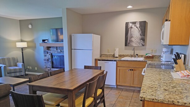 A compact kitchen with a dining area, a refrigerator, a dishwasher, and a microwave.
