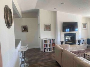 Un salon comprenant un canapé, une bibliothèque, un téléviseur à écran plat, une cheminée et un coin repas.