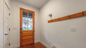 A hallway with a wooden door, a coat rack, and a small wooden bench. - Evergreen Retreat A 30 Night Minimum (White Salmon)