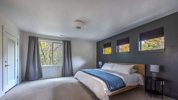 A bedroom with a bed, a window with curtains, a wall-mounted lamp, and a ceiling light. - Evergreen Retreat A 30 Night Minimum (White Salmon)