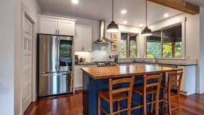 A modern kitchen with a large island, stainless steel appliances, and wooden bar stools. - Evergreen Retreat A 30 Night Minimum (White Salmon)
