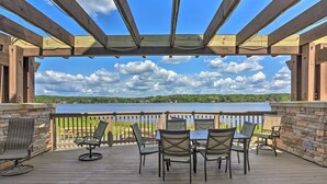 Eine überdachte Terrasse im Freien mit Tisch und Stühlen, mit Blick auf ein Gewässer.