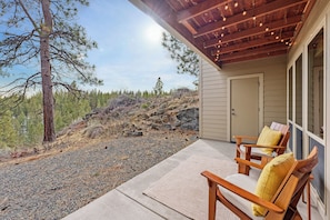 A covered outdoor area with a concrete floor, wooden chairs with cushions, and a door leading to a building. - Seventh Mountain 1417 (Bend)