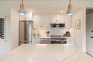 Una cocina moderna con gabinetes blancos, electrodomésticos de acero inoxidable y una isla de mármol.