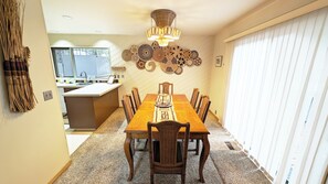 A dining area with a wooden table, chairs, a chandelier, and wall decor.