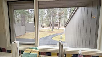 A window with a view of a backyard, a wooden fence, and a paved path.