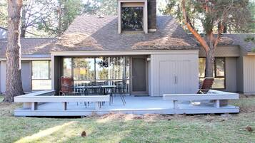 A modern house with a covered patio, a dining area with outdoor furniture, and a chimney.