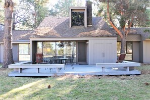 A modern house with a covered patio, a dining area with outdoor furniture, and a chimney. - Meadow House 42 (Bend)