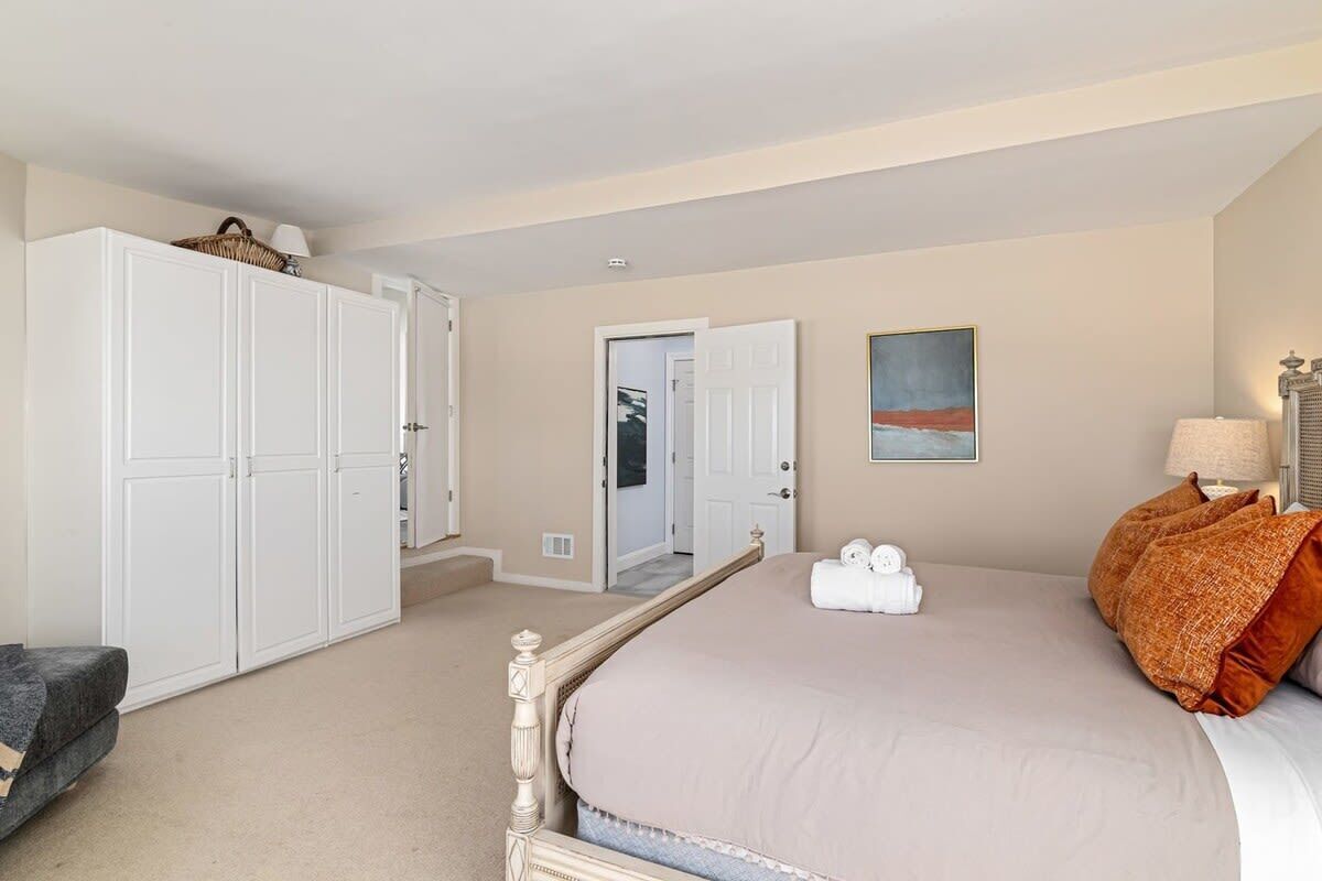 A bedroom with a large bed, a wardrobe, and a mirror.