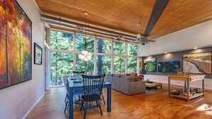 A modern interior with a dining area, kitchen, and large windows. - Happenstance Vineyards King Rooms (Mosier)