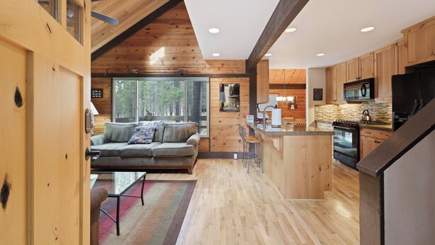 A spacious kitchen with wooden cabinets, a large island, and a built-in oven. - Pole House 10 (Bend)