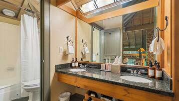 A bathroom with a wooden vanity, two sinks, a large mirror, and a shower area.