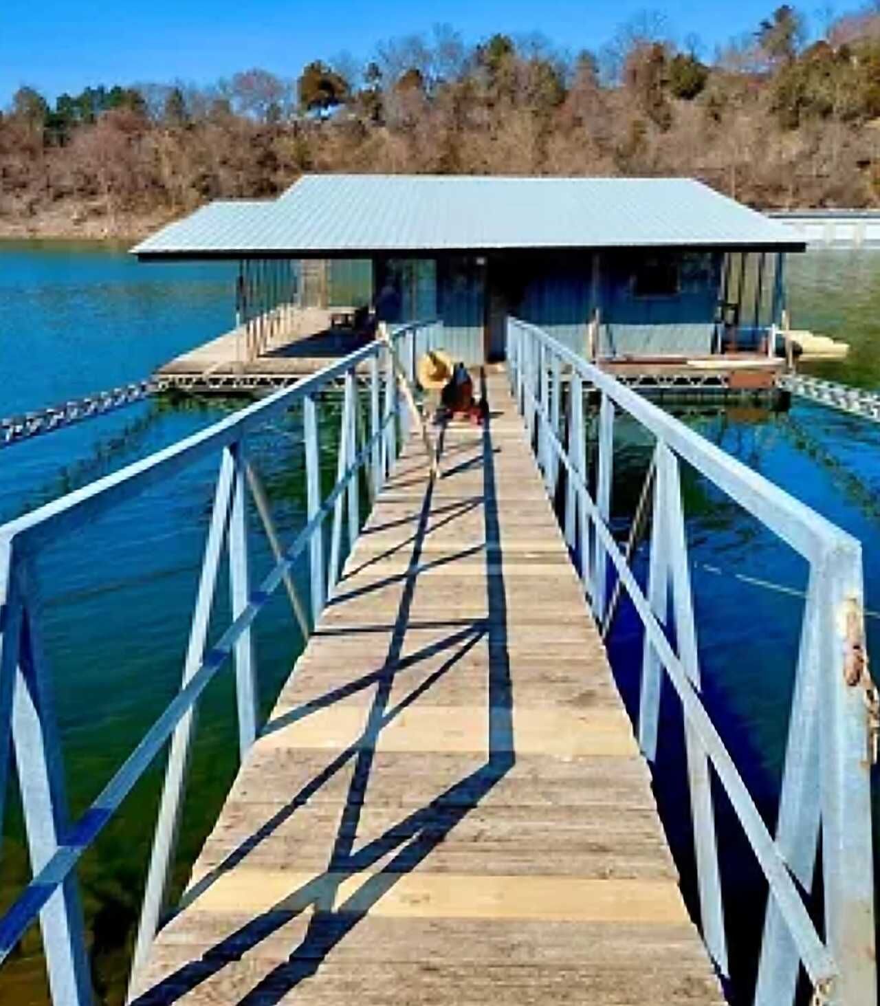 A wooden pier leading to a building with a metal roof, surrounded by water.