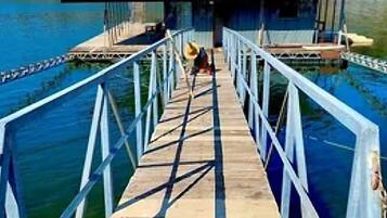 A wooden pier leading to a building with a metal roof, surrounded by water.