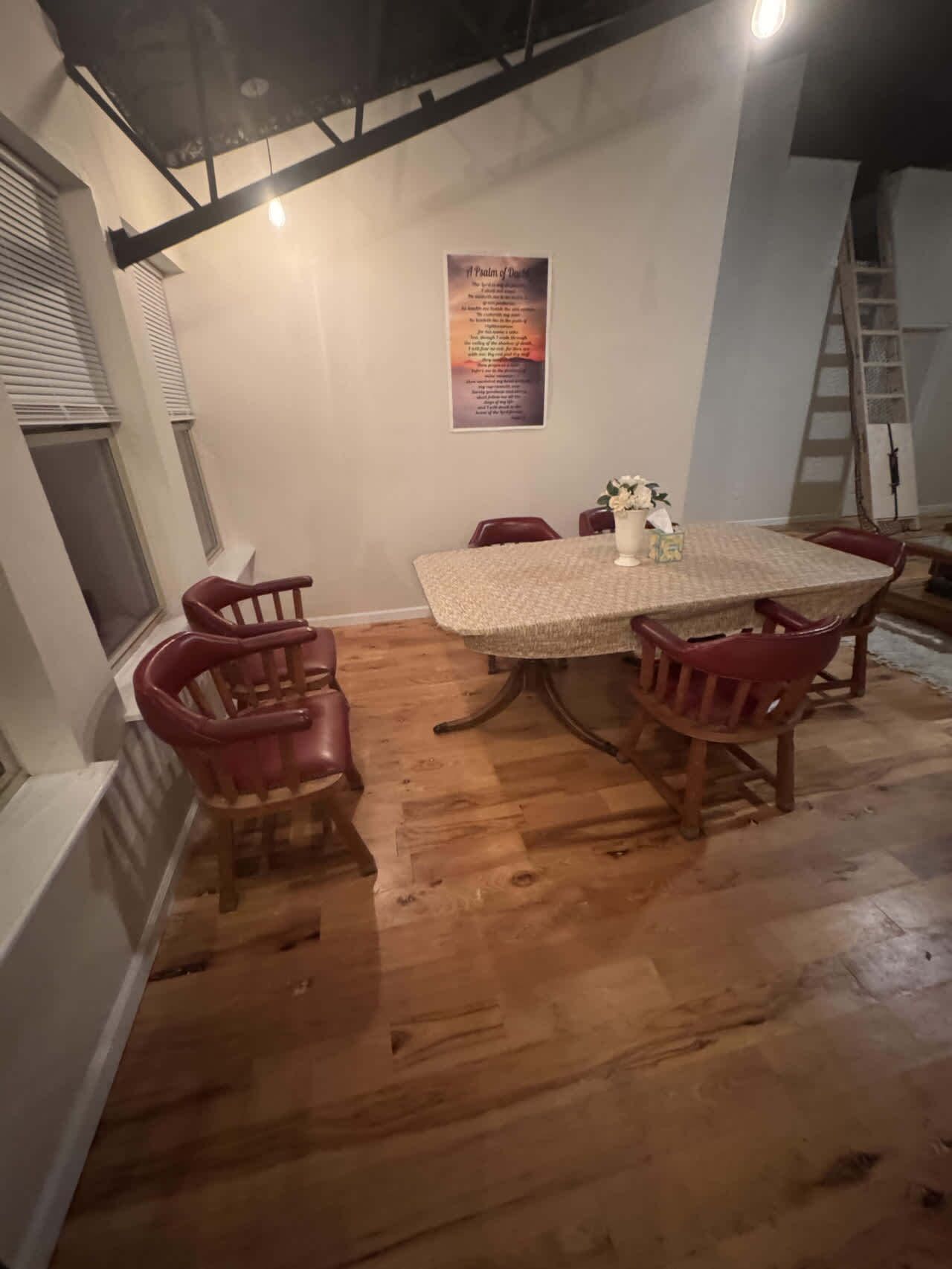 Een eetgedeelte met een ronde tafel, zes stoelen en een poster aan de muur.