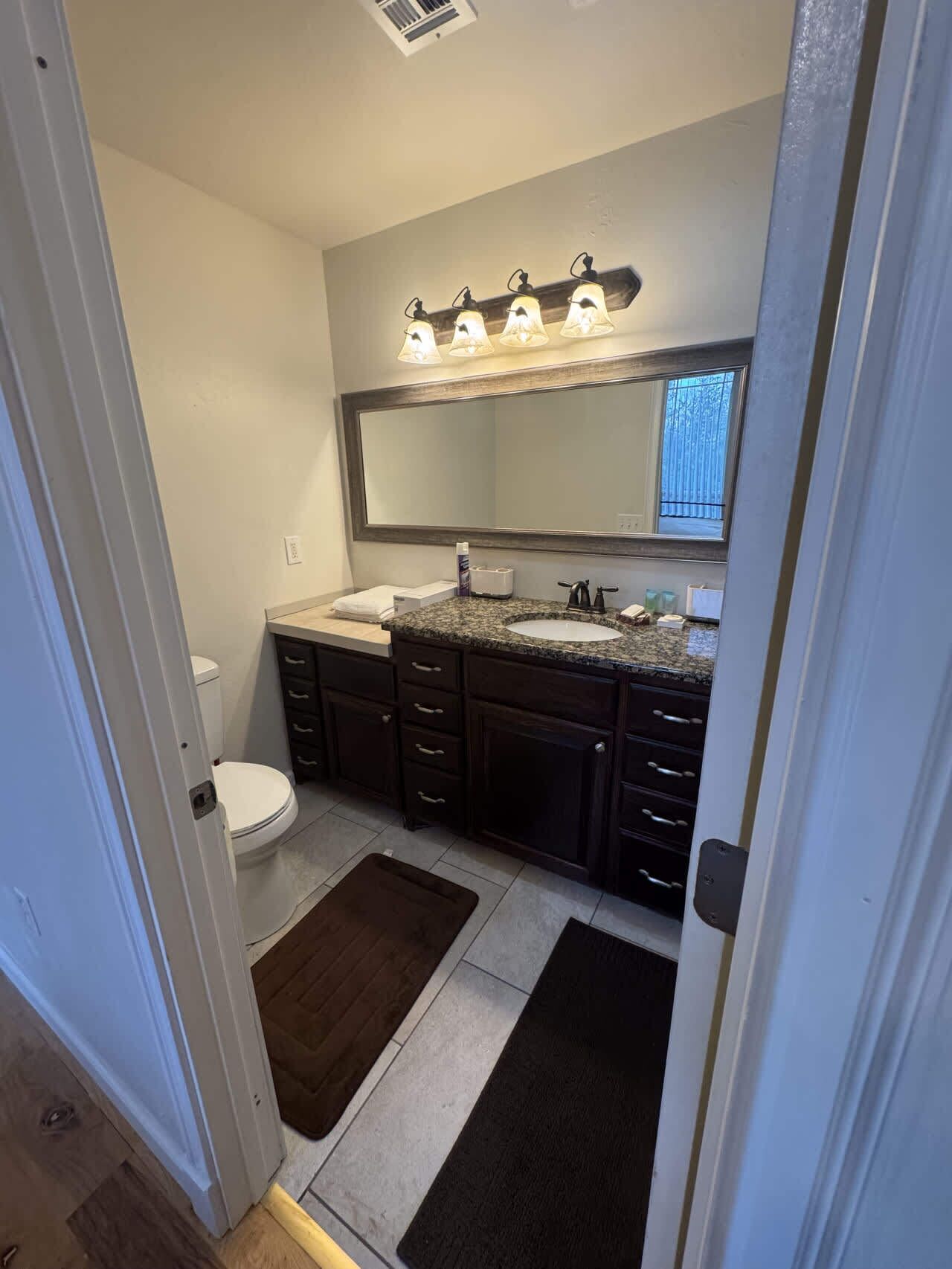 Une salle de bain comprenant des toilettes, un lavabo, un meuble-lavabo et un grand miroir.