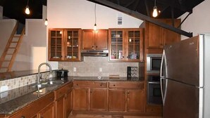Una cocina con armarios de madera, un refrigerador de acero inoxidable y un horno empotrado.