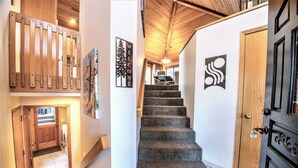 A staircase leading to a second floor, a wooden door, and a welcome sign. - Red Cedar 53 (Bend)