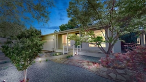 A modern house with a covered porch, a gravel driveway, and landscaped garden with trees and shrubs. - Marbella Lane - SJ Designer Home 3BR Ldry P (San Jose)